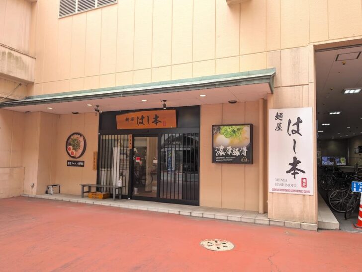 パチンコ玉屋の駐輪場横に、麺屋はし本の看板が見えてくる