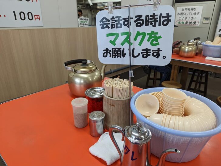 赤いテーブル、やかん入りのぬるいお茶、ザルに入った湯のみなど、長浜屋で見慣れた光景